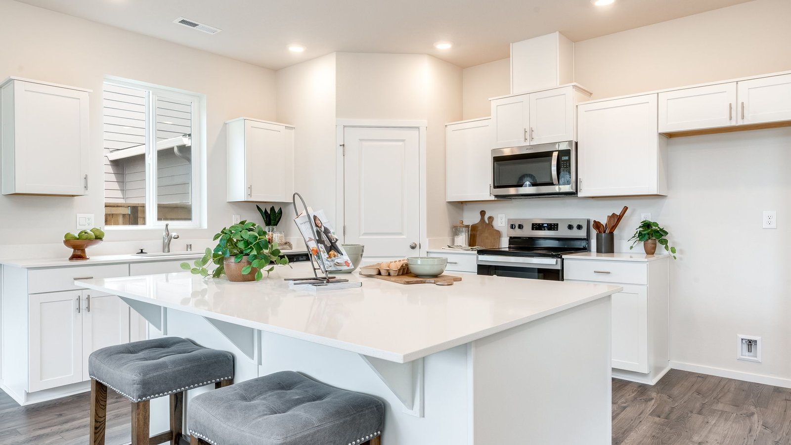 Kitchen with shaker cabinets, quartz counters, stainless steel appliances, pantry, and an island with a breakfast bar