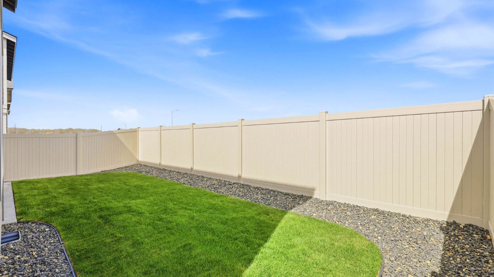 backyard with sod and vinyl plank fence and covered patio