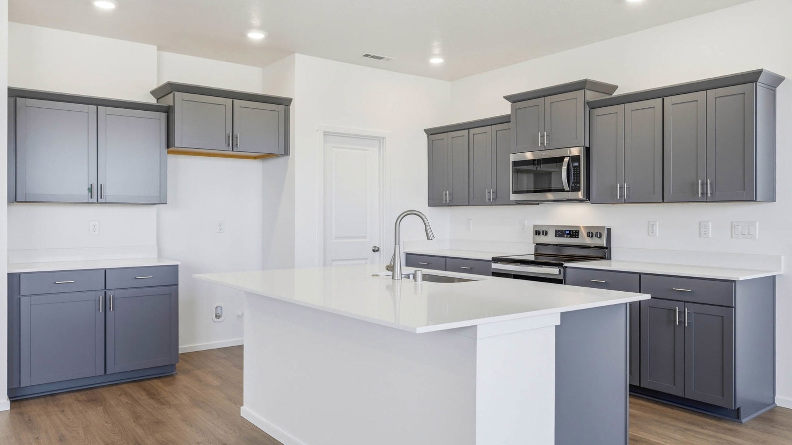 Kitchen with shaker cabinets, quartz counters, stainless steel appliances, pantry, and an island with a breakfast bar