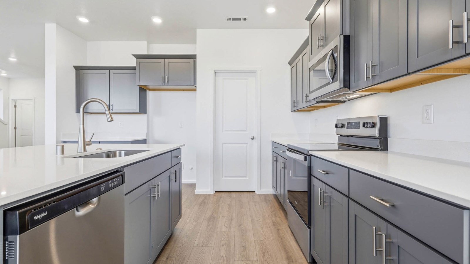 Kitchen with shaker cabinets, quartz counters, stainless steel appliances, pantry, and an island with a breakfast bar