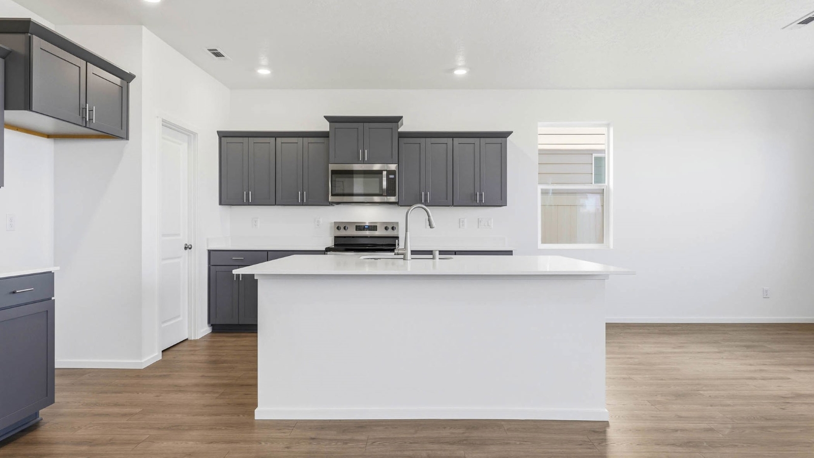 Kitchen with shaker cabinets, quartz counters, stainless steel appliances, pantry, and an island with a breakfast bar