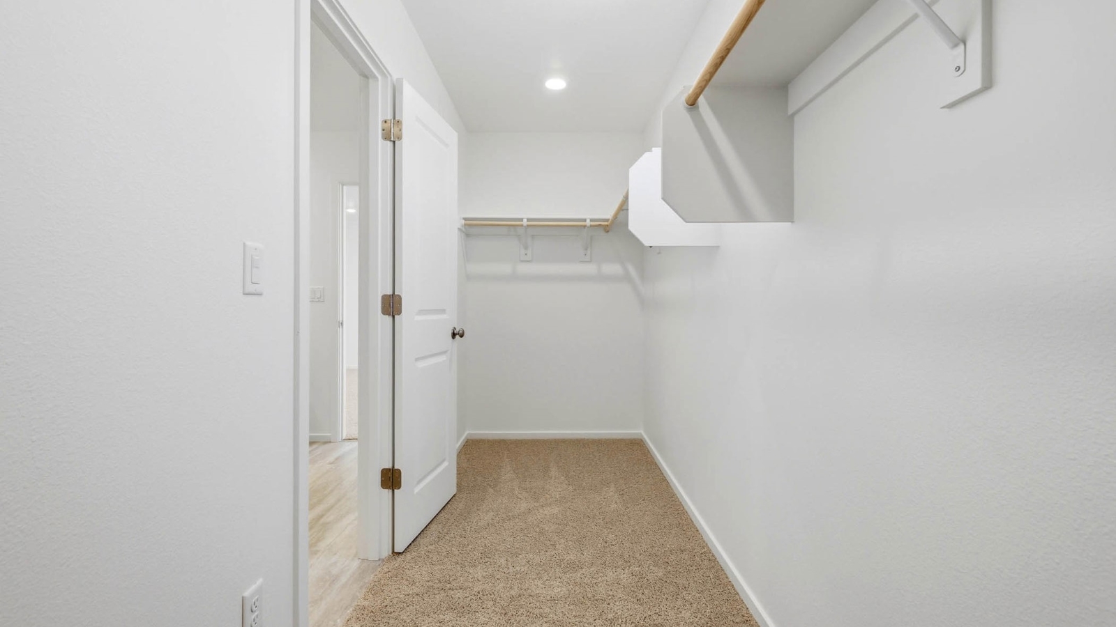 Primary bedroom walk-in closet with built-in shelves