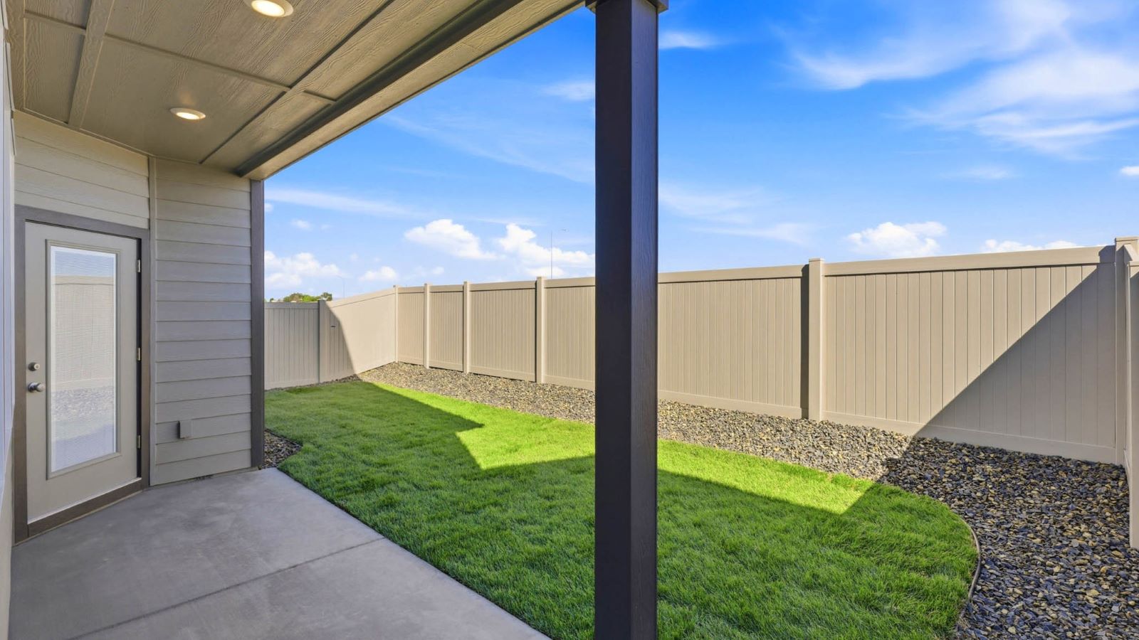 backyard with sod and vinyl plank fence and covered patio