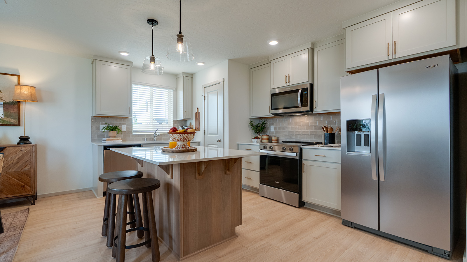 Kitchen with shaker cabinets, quartz counters, stainless steel appliances, pantry, and an island with a breakfast bar