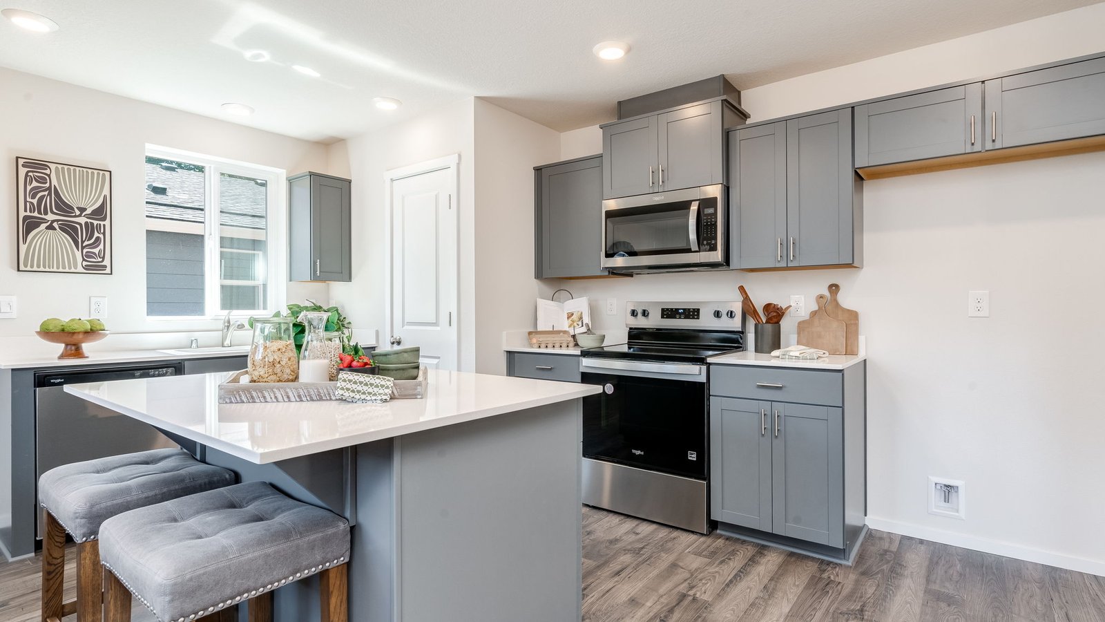 Kitchen with shaker cabinets, quartz counters, stainless steel appliances, pantry, and an island with a breakfast bar