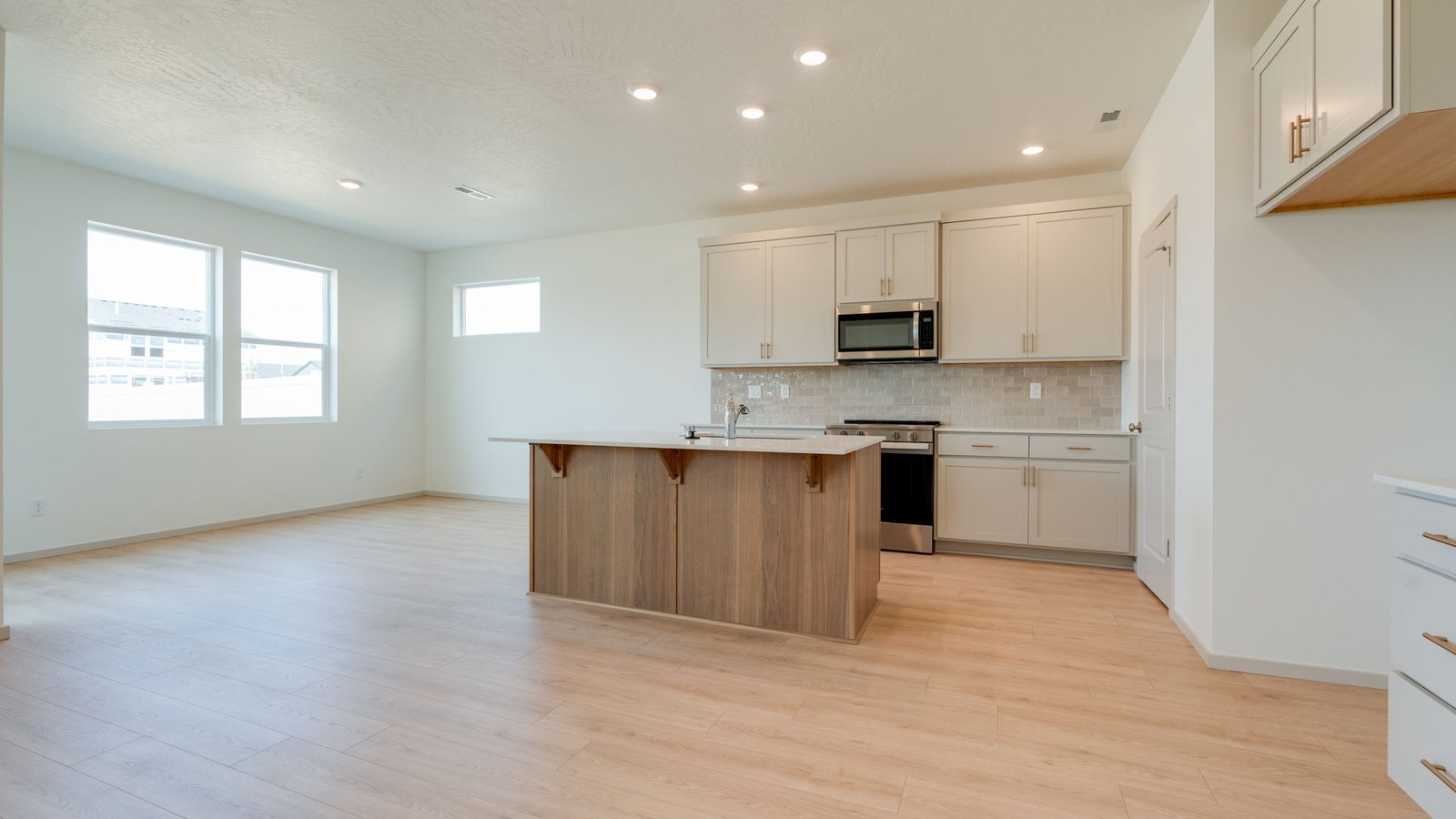 Kitchen with shaker cabinets, quartz counters, stainless steel appliances, pantry, and an island with a breakfast bar