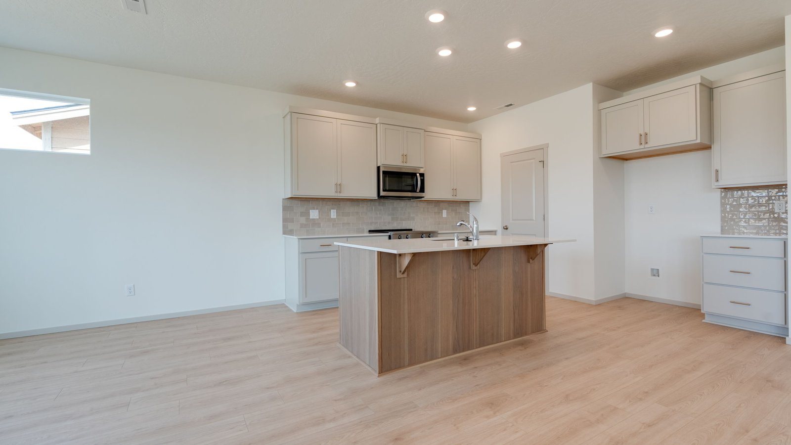 Kitchen with shaker cabinets, quartz counters, stainless steel appliances, pantry, and an island with a breakfast bar