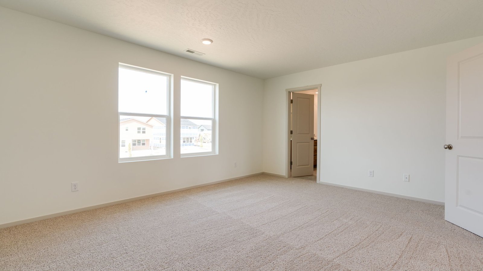 Primary bedroom with wall-to-wall carpet, a walk-in closet and an attached bathroom