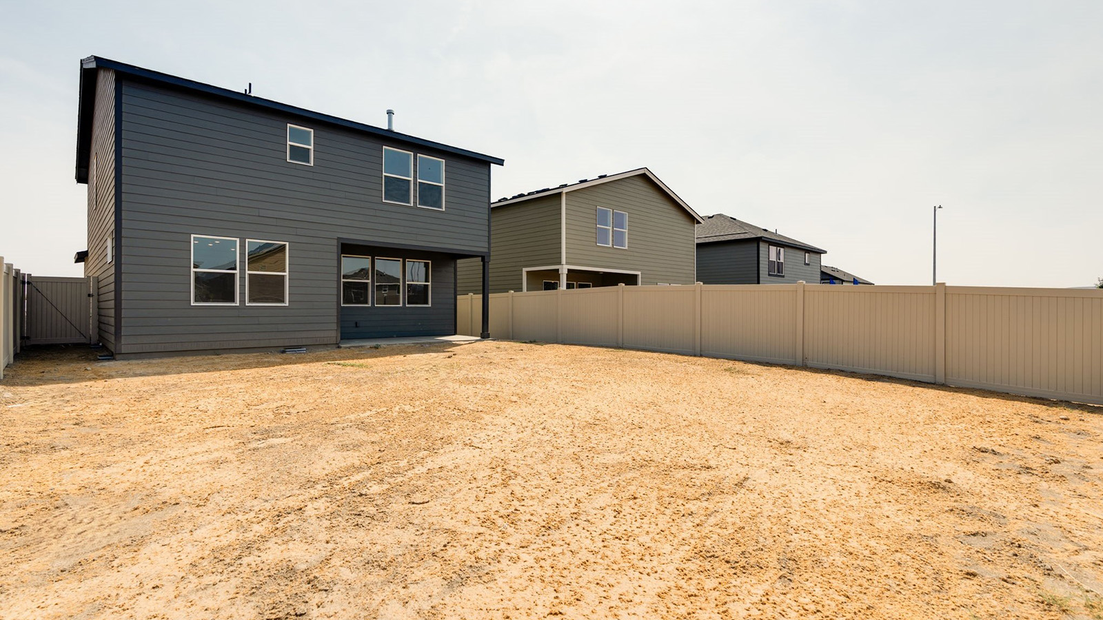 fully fenced backyard with bark chips and a patio