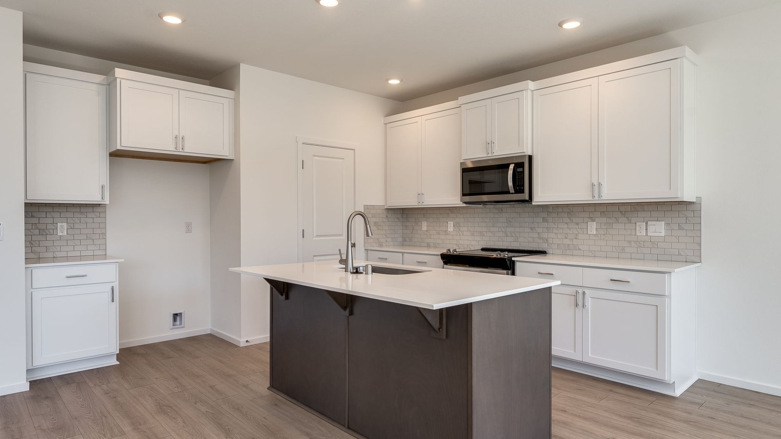 Kitchen with shaker cabinets, quartz counters, stainless steel appliances, pantry, and an island with a breakfast bar