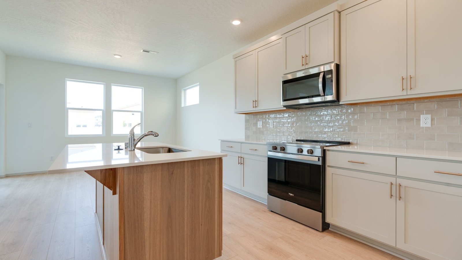 Kitchen with shaker cabinets, quartz counters, stainless steel appliances, pantry, and an island with a breakfast bar