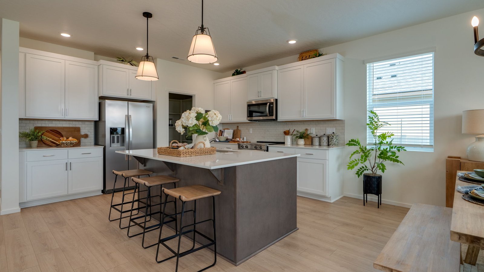 Kitchen with shaker cabinets, quartz counters, stainless steel appliances, pantry, and an island with a breakfast bar