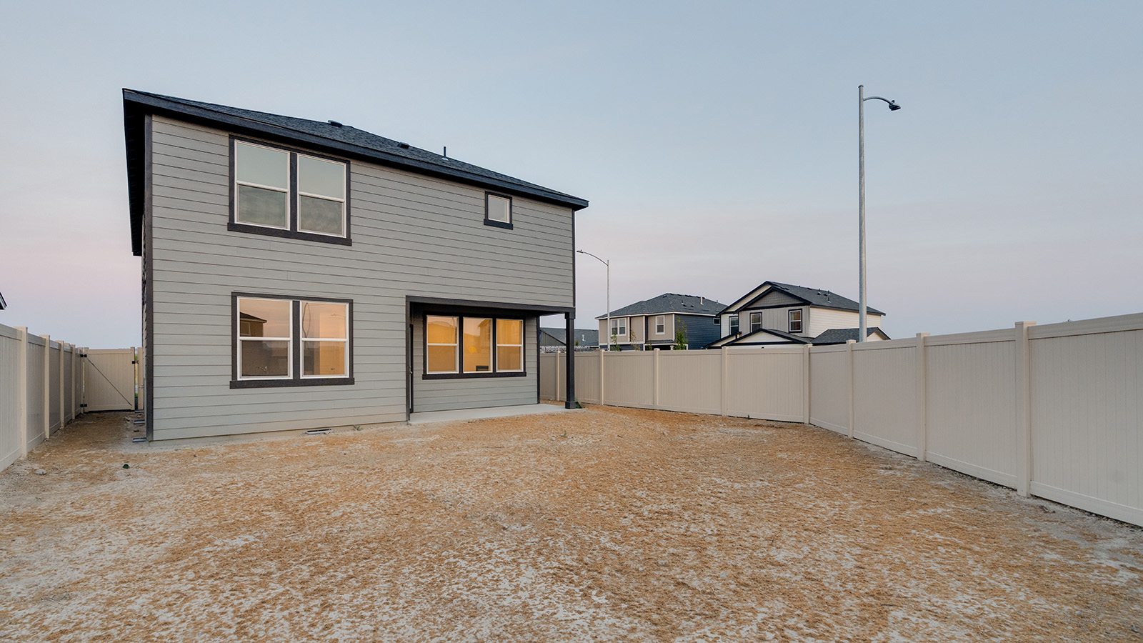 fully fenced backyard with bark chips and a patio