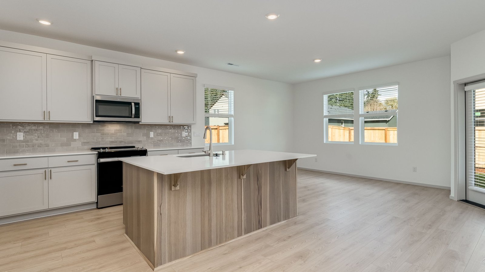 Kitchen with shaker cabinets, quartz counters, stainless steel appliances, pantry, and an island with a breakfast bar