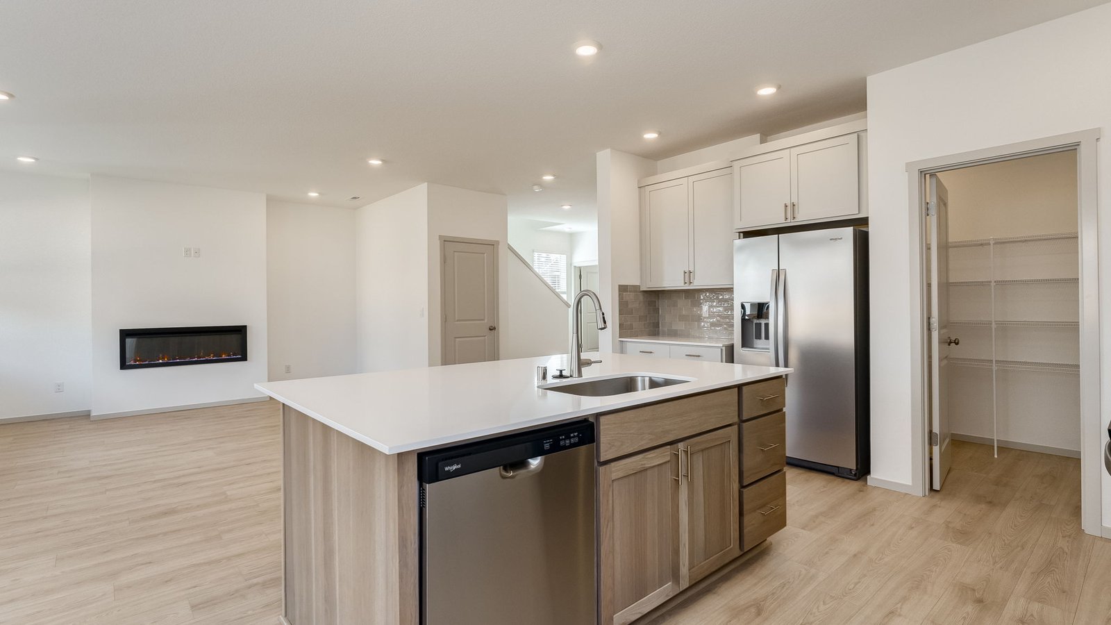 Kitchen with shaker cabinets, quartz counters, stainless steel appliances, pantry, and an island with a breakfast bar