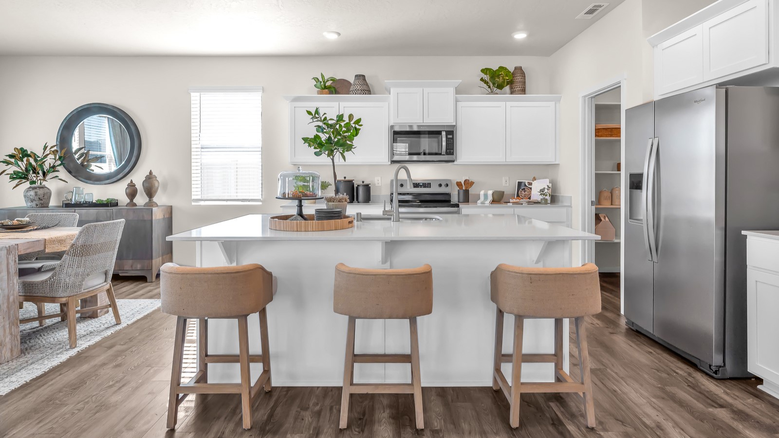 Kitchen with shaker cabinets, quartz counters, stainless steel appliances, pantry, and an island with a breakfast bar
