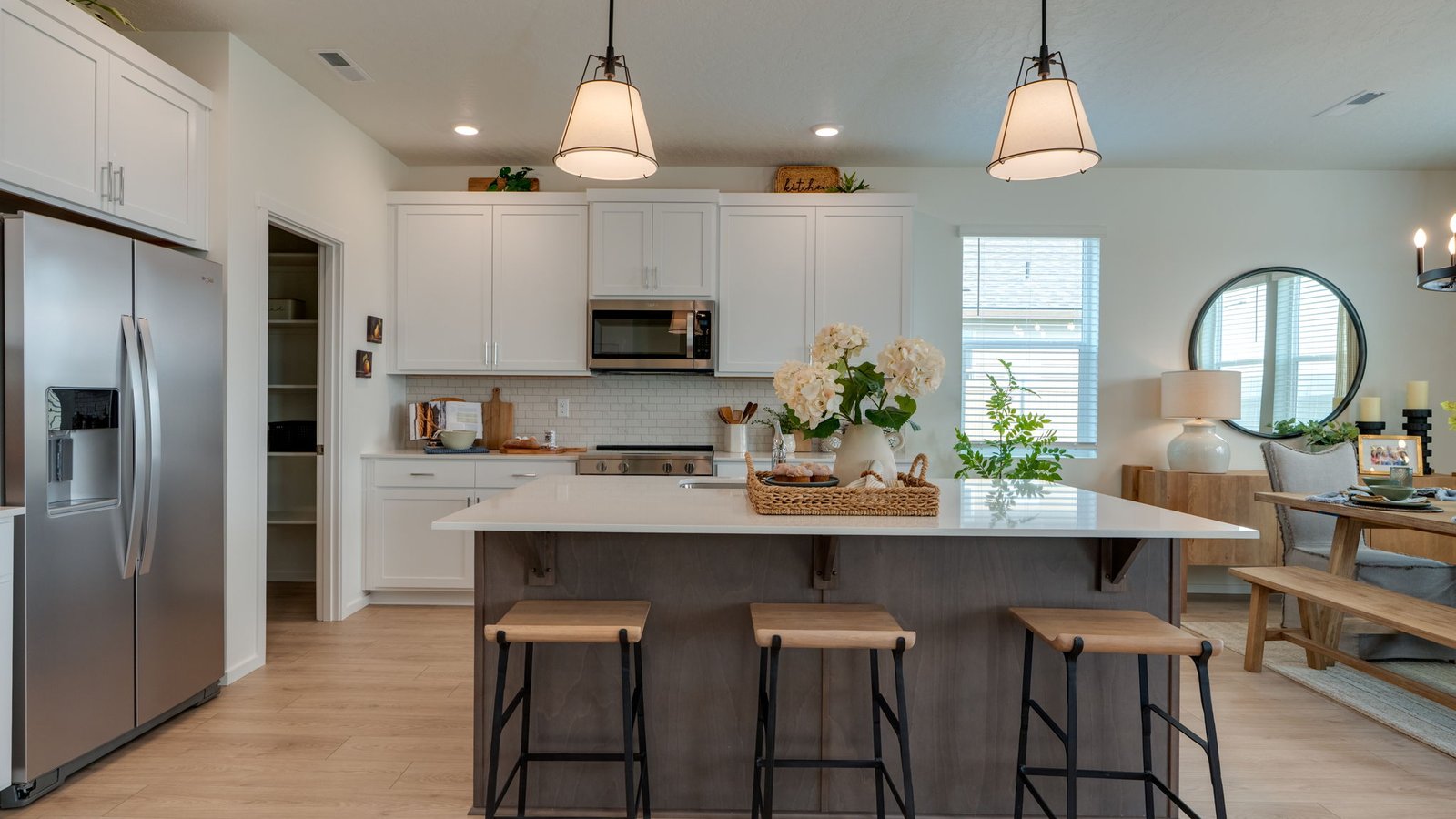 Kitchen with shaker cabinets, quartz counters, stainless steel appliances, pantry, and an island with a breakfast bar