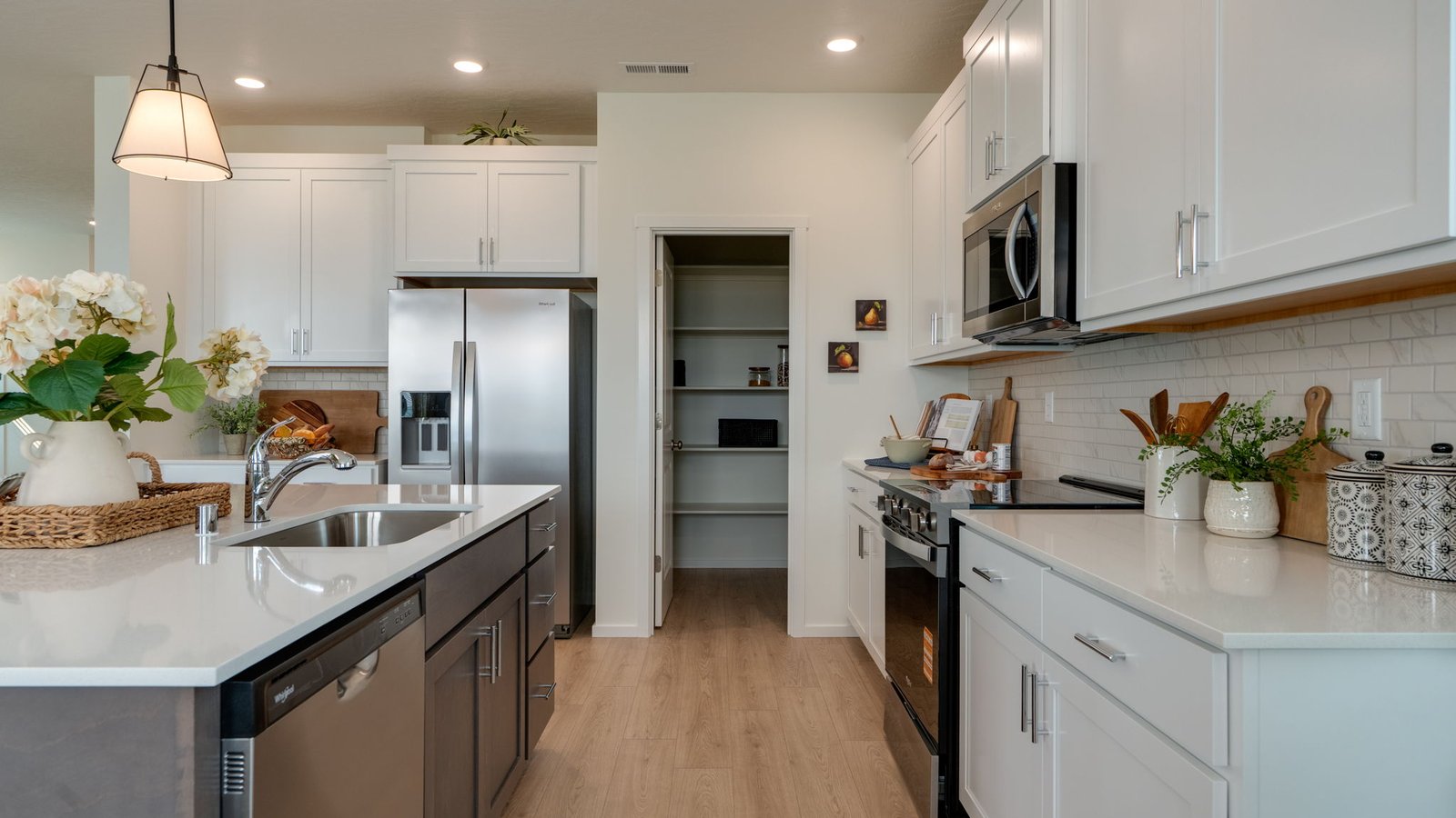 Kitchen with shaker cabinets, quartz counters, stainless steel appliances, pantry, and an island with a breakfast bar