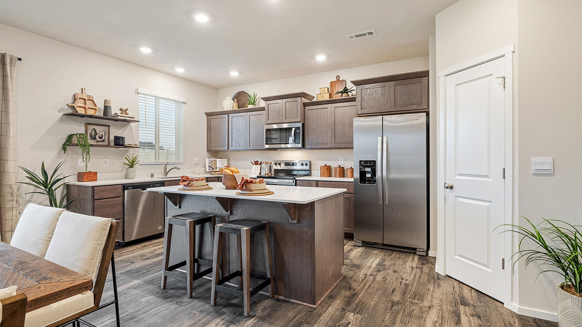 Kitchen with shaker cabinets, quartz counters, stainless steel appliances, pantry, and an island with a breakfast bar