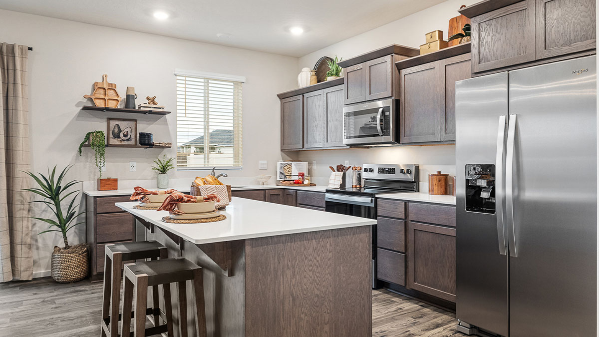 Kitchen with shaker cabinets, quartz counters, stainless steel appliances, pantry, and an island with a breakfast bar