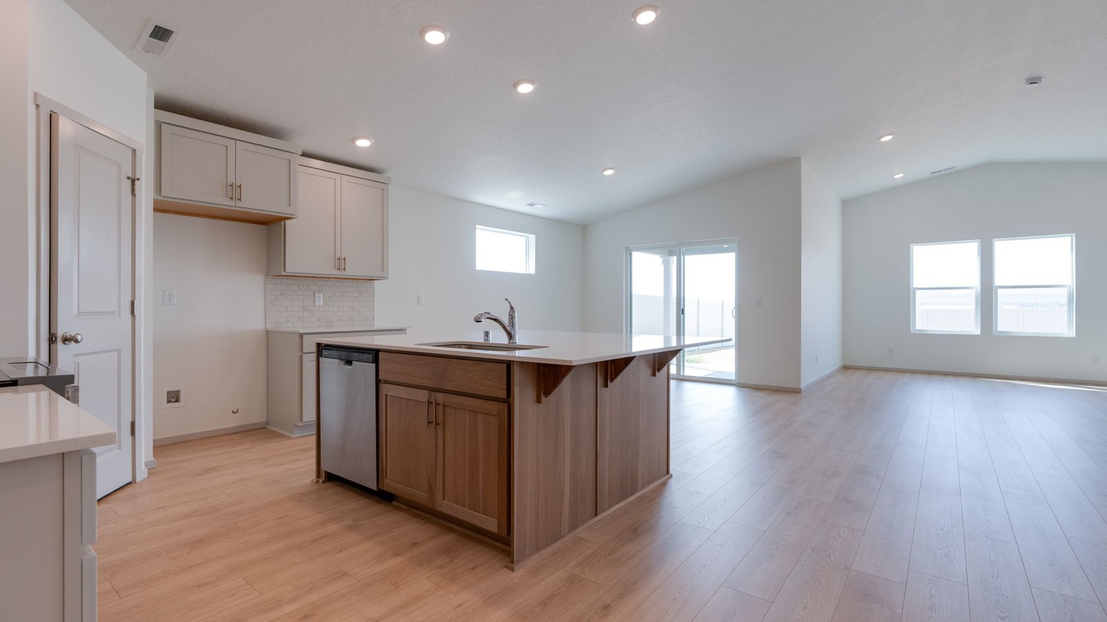Kitchen with shaker cabinets, quartz counters, stainless steel appliances, pantry, and an island with a breakfast bar