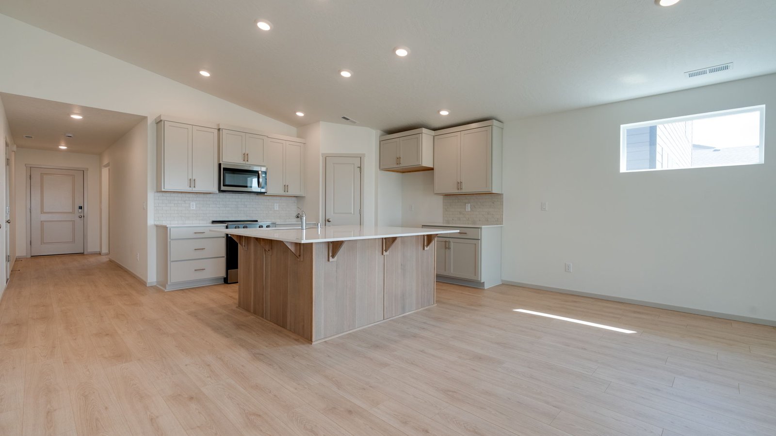 Kitchen with shaker cabinets, quartz counters, stainless steel appliances, pantry, and an island with a breakfast bar