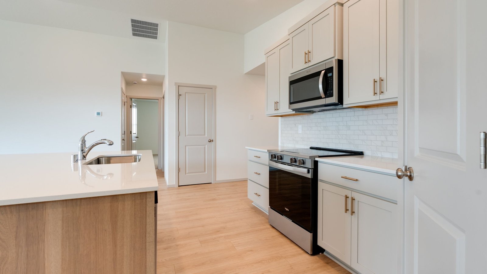 Kitchen with shaker cabinets, quartz counters, stainless steel appliances, pantry, and an island with a breakfast bar