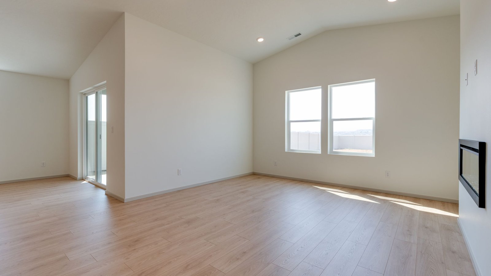Great room with laminate flooring and an electric fireplace and vaulted ceilings