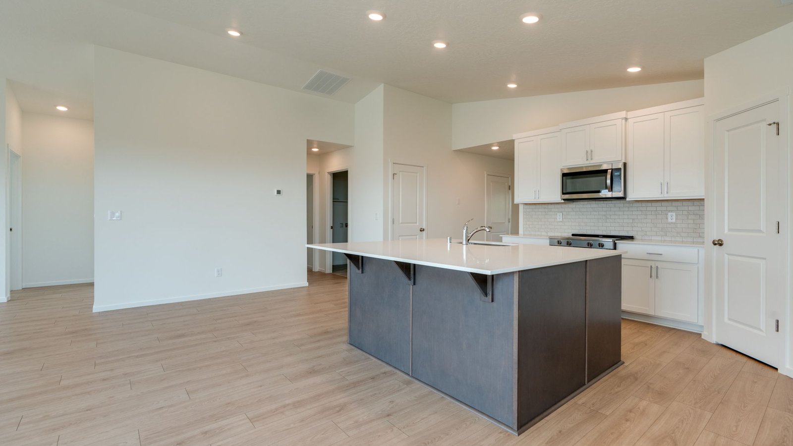 Kitchen with shaker cabinets, quartz counters, stainless steel appliances, pantry, and an island with a breakfast bar