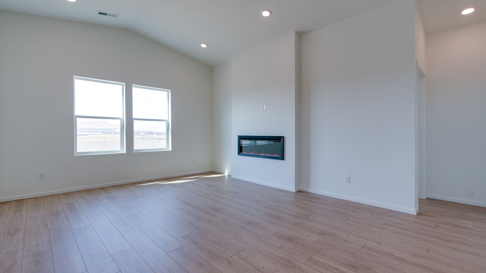 Great room with laminate flooring and an electric fireplace and vaulted ceilings