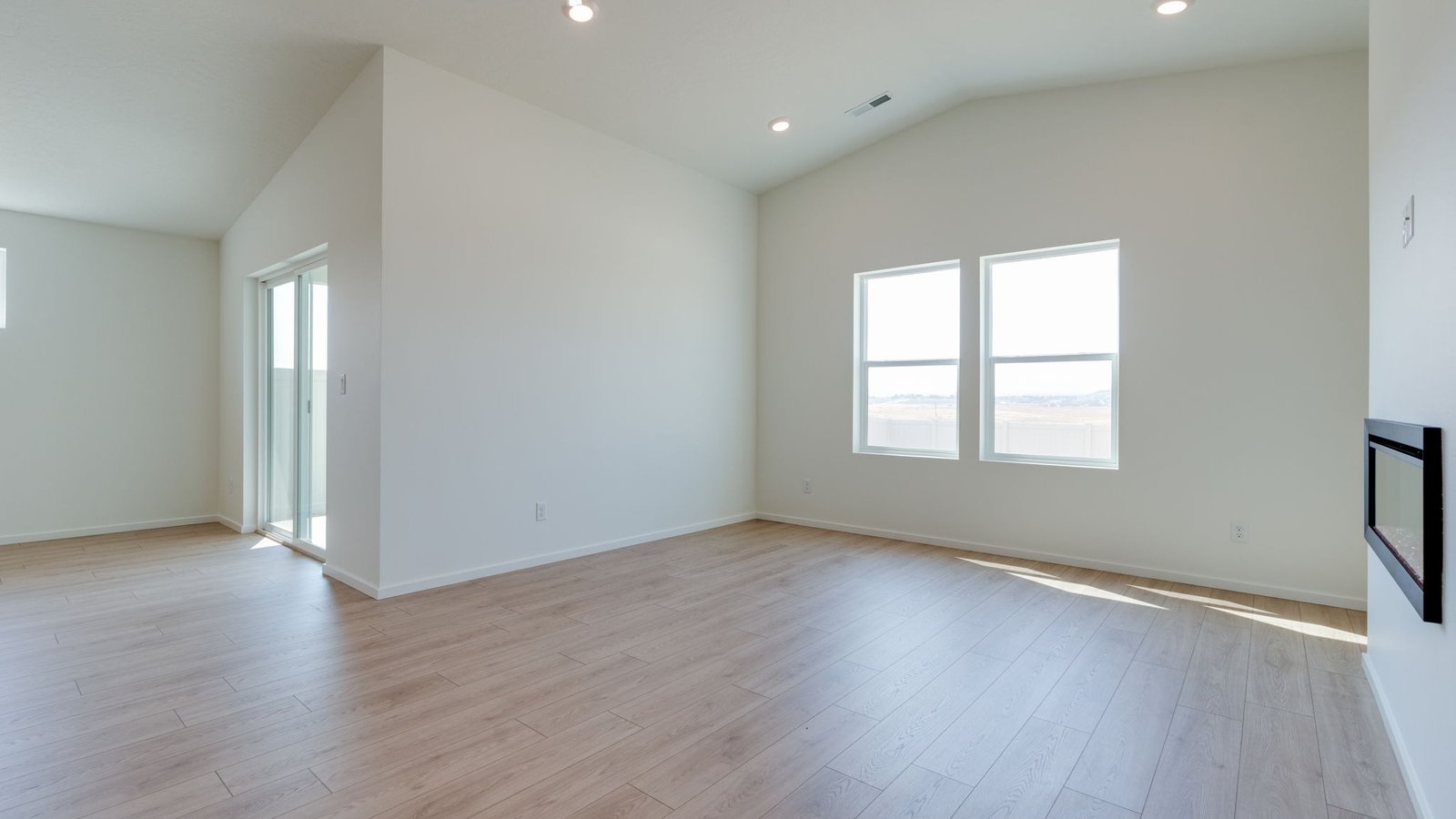 Great room with laminate flooring and an electric fireplace and vaulted ceilings