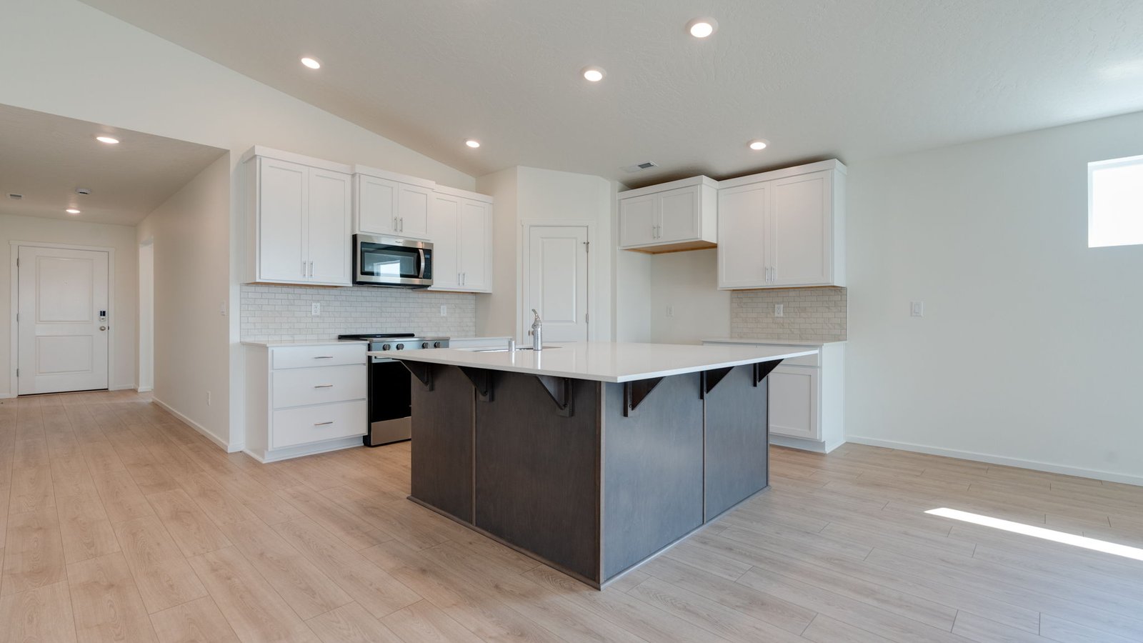 Kitchen with shaker cabinets, quartz counters, stainless steel appliances, pantry, and an island with a breakfast bar