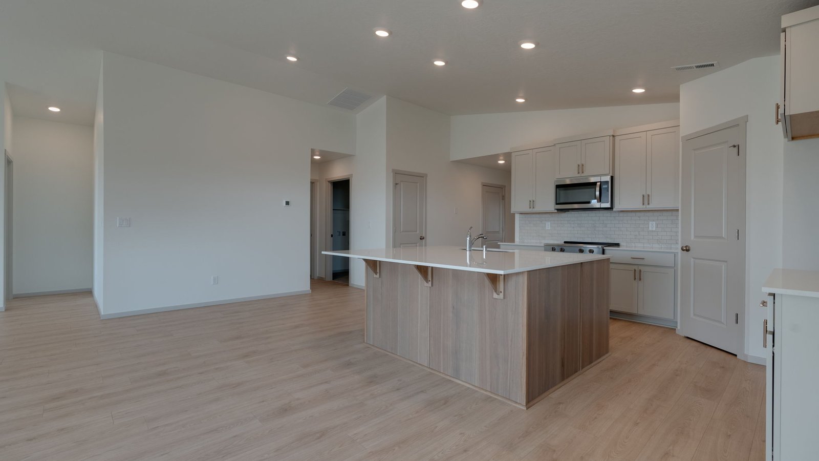 Kitchen with shaker cabinets, quartz counters, stainless steel appliances, pantry, and an island with a breakfast bar