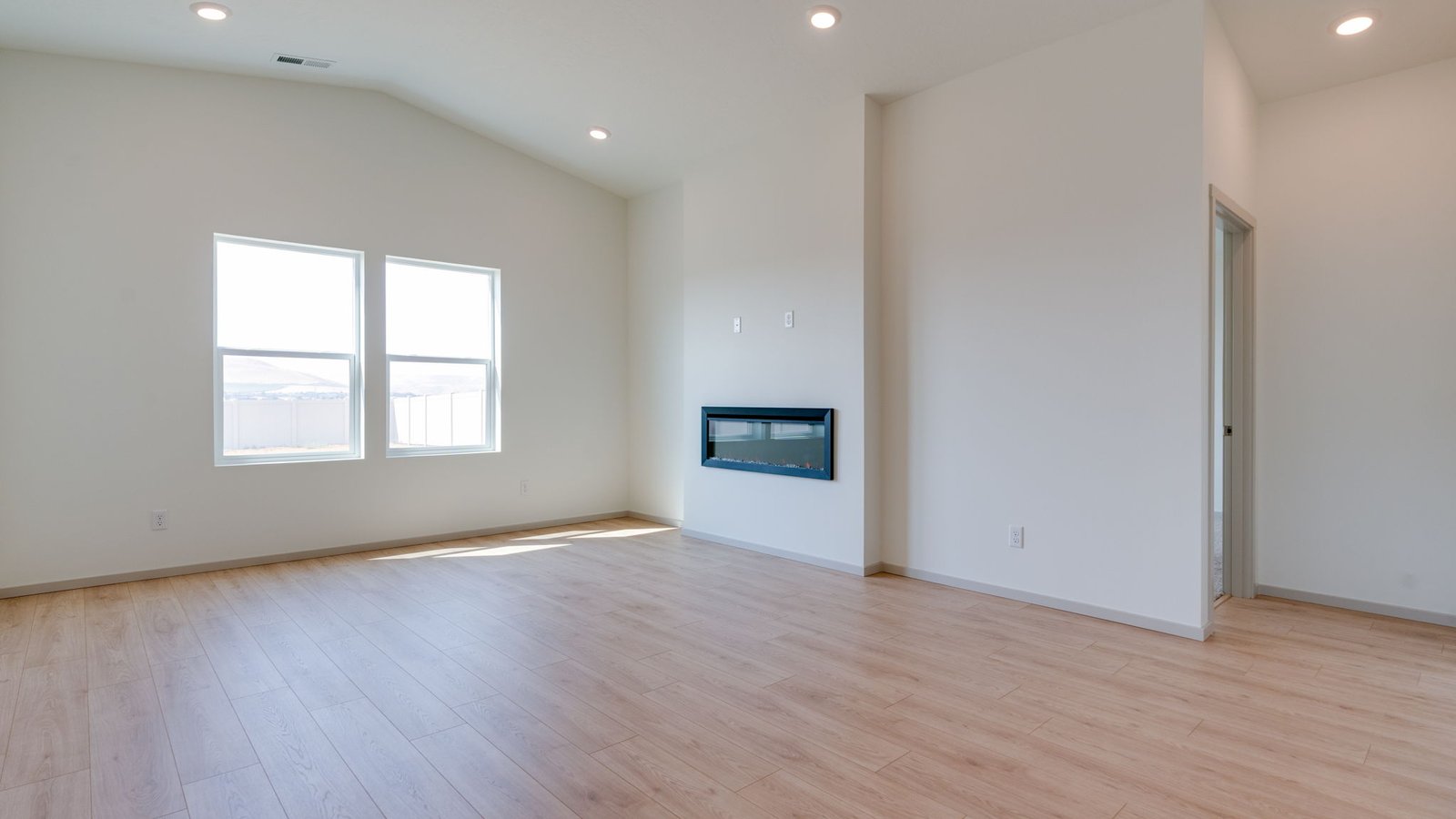 Great room with laminate flooring and an electric fireplace and vaulted ceilings