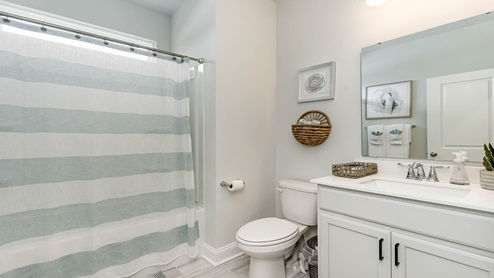 secondary bathroom with white cabinets and shower tub combo