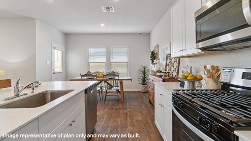Spacious kitchen with stainless steel appliances and hard surface flooring.