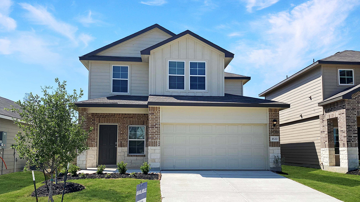 Two story home with covered porch, brick and stucco front exterior and two car garage.