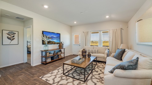 Floresville Links at River Bend New Construction Homes spatial living area with white couch and back door