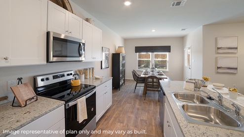 DR Horton Von Ormy Preserve at Medina the nicole floor plan 2473 square feet open concept kitchen with white cabinets stainless steel appliances and granite countertops flowing to dining area with farm style table