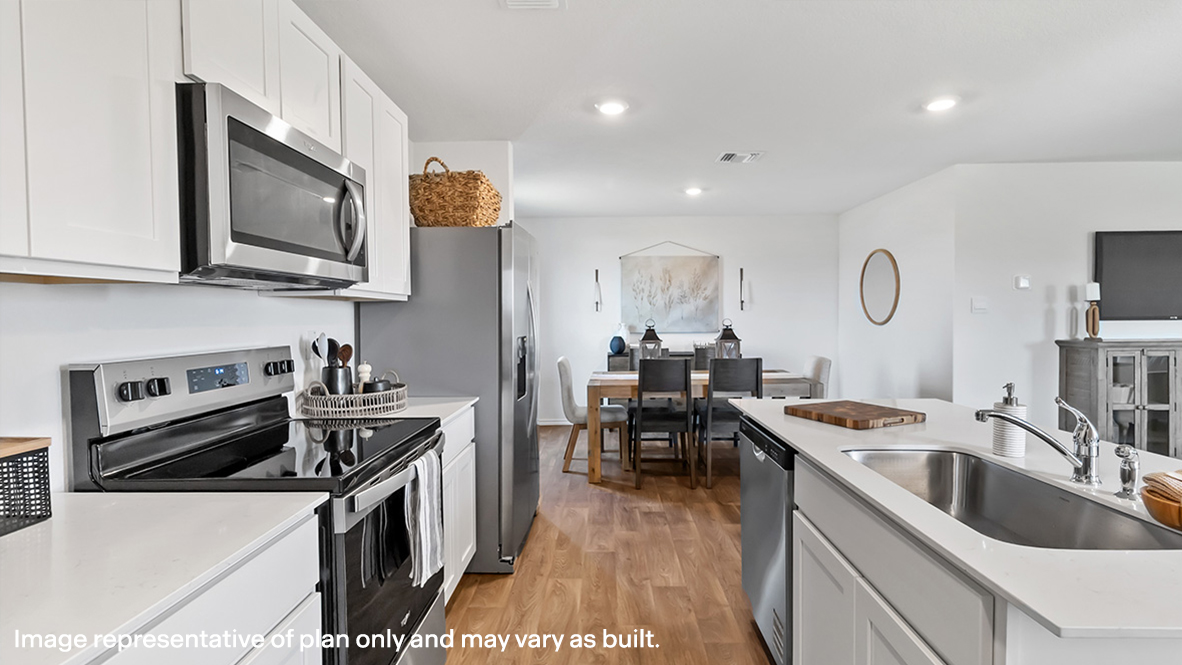 New appliances and central kitchen island with seating anchor the kitchen, next to dining, great room, backyard access