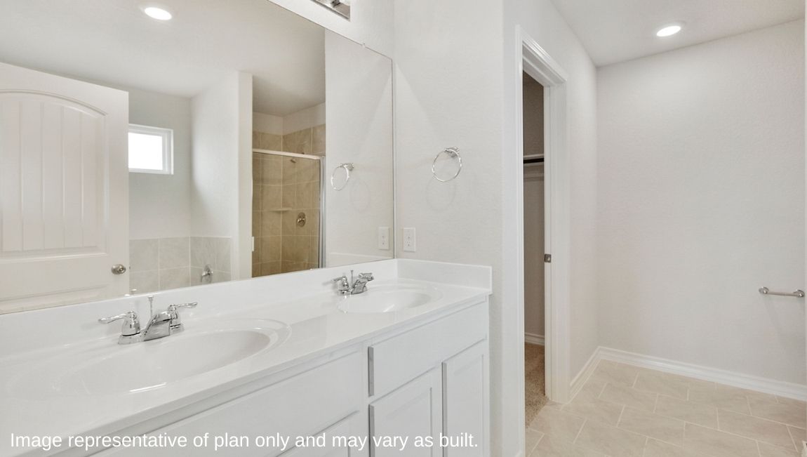 Bathroom with dual sinks and a walk in closet.