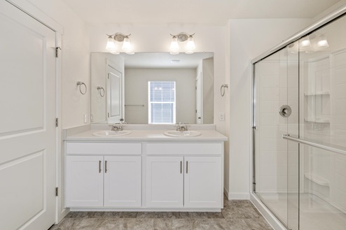 white cabinet bathroom with two sinks and a shower