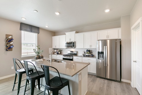 kitchen with white cabinets, stainless steel appliances and barstools