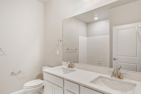 white cabinet bathroom with dual-basin sink, mirror and toilet