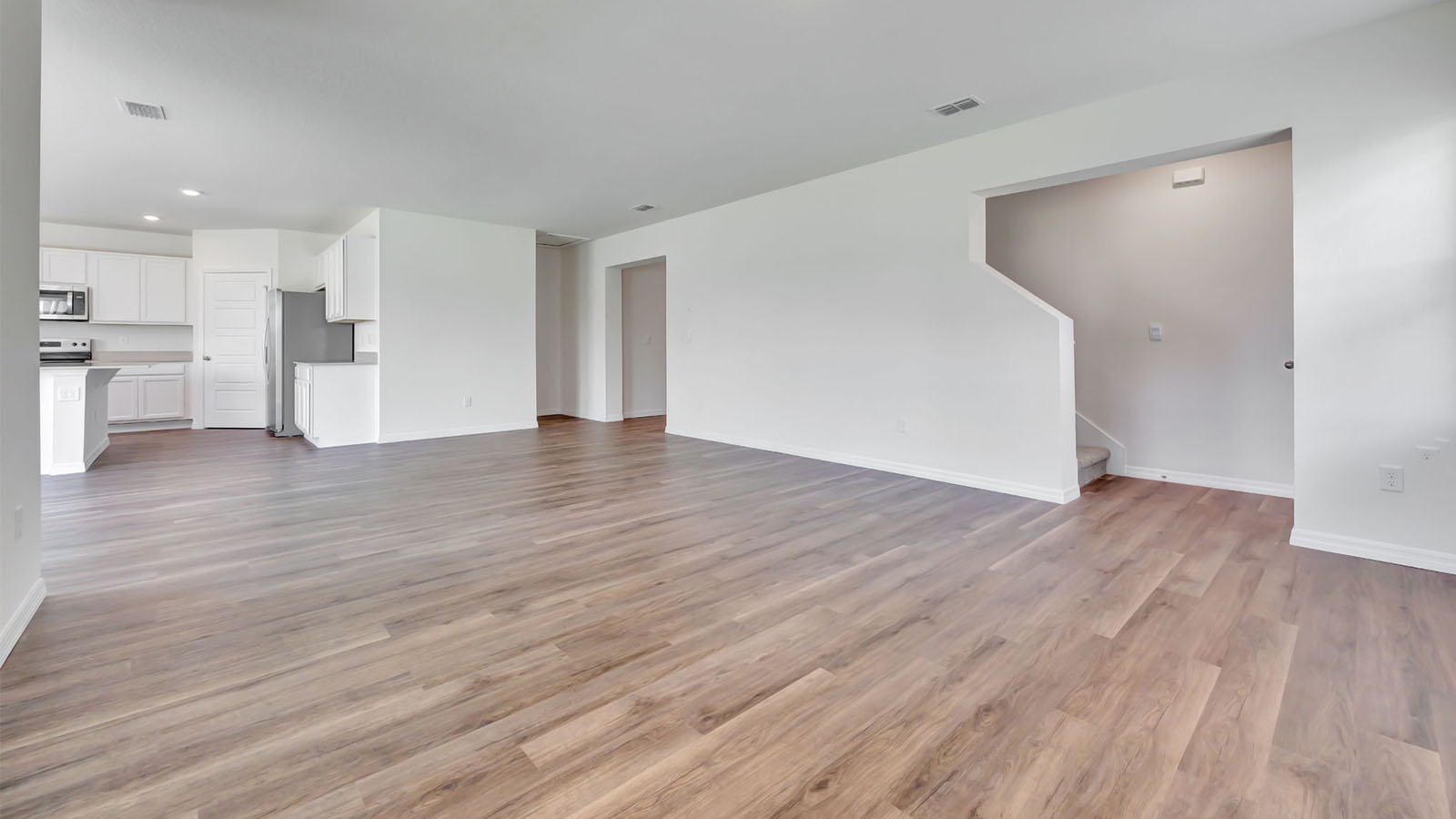 Living room with stair access to the second-floor and view to the kitchen