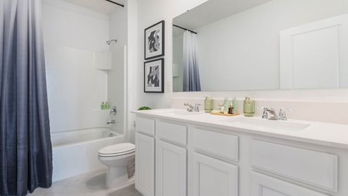 Upstairs guest bathroom with double vanity sinks and tub