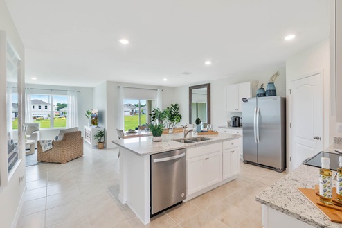 Kitchen island with white cabinets and stainless steel appliances looking into the dining room