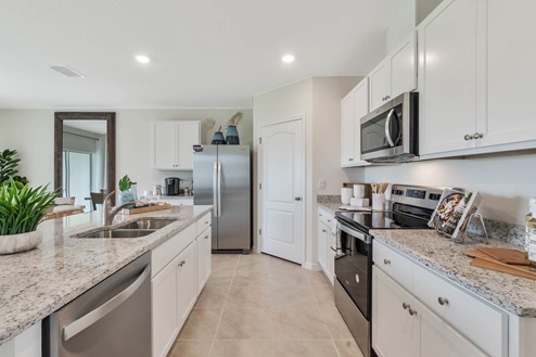 Kitchen with white cabinets, pantry, and stainless steel appliances