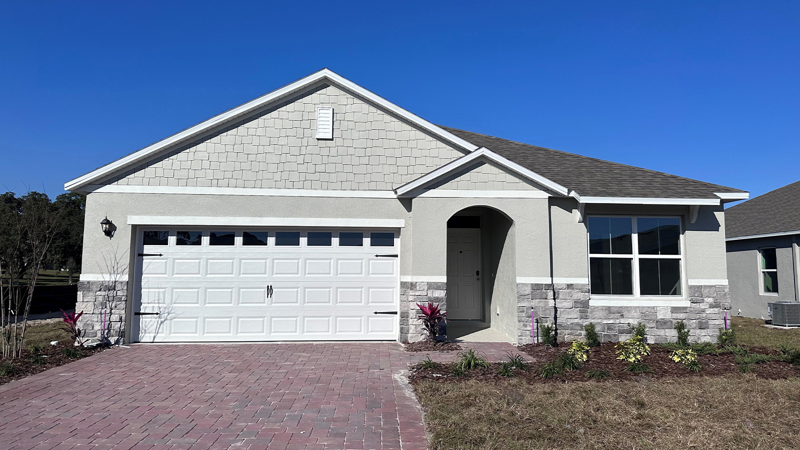 Front Exterior Image of a Single Family Home with 2-car Garage, stone accents, and paver driveway