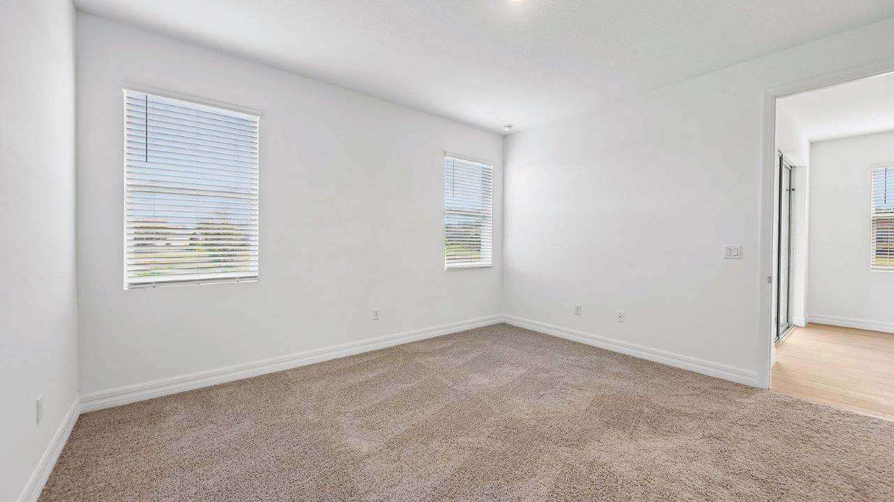 Primary bedroom with carpet flooring and 2 windows